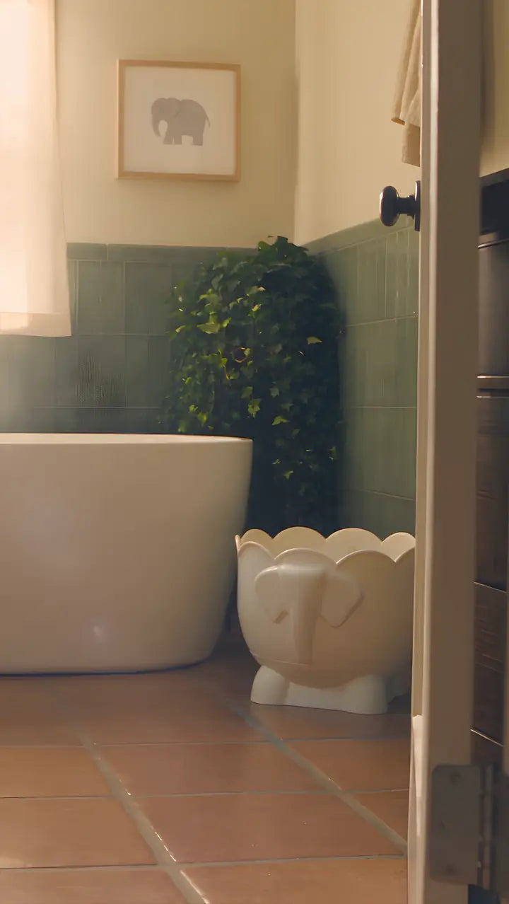 A warm, sunlit bathroom with a freestanding tub and a sheer curtain over the window.