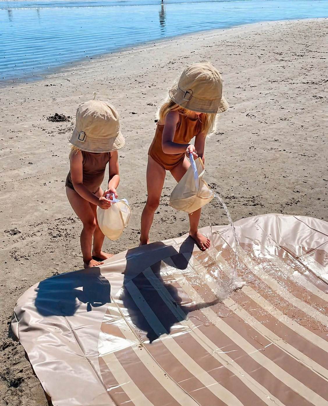 The Tiipikids Beach Pool in Stone, set up on a beach with two children filling it.