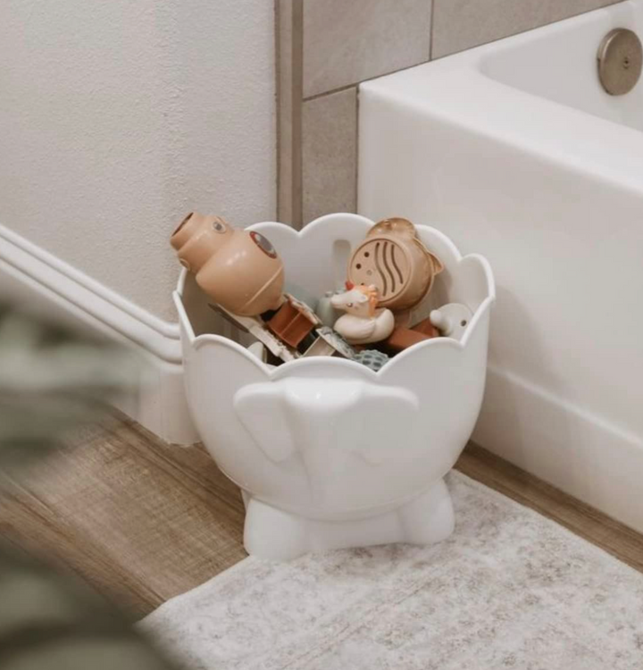 Bath Buddy in a bathroom corner, holding a pile of bath toys