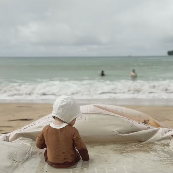 Toddler sitting in the Tiipikids portable baby pool at the beach — no-hose kiddie pool for travel and outdoor backyard play