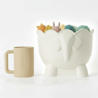 The off-white silicone rinse cup standing beside the Bath Buddy organizer, which holds a set of bath toys.
