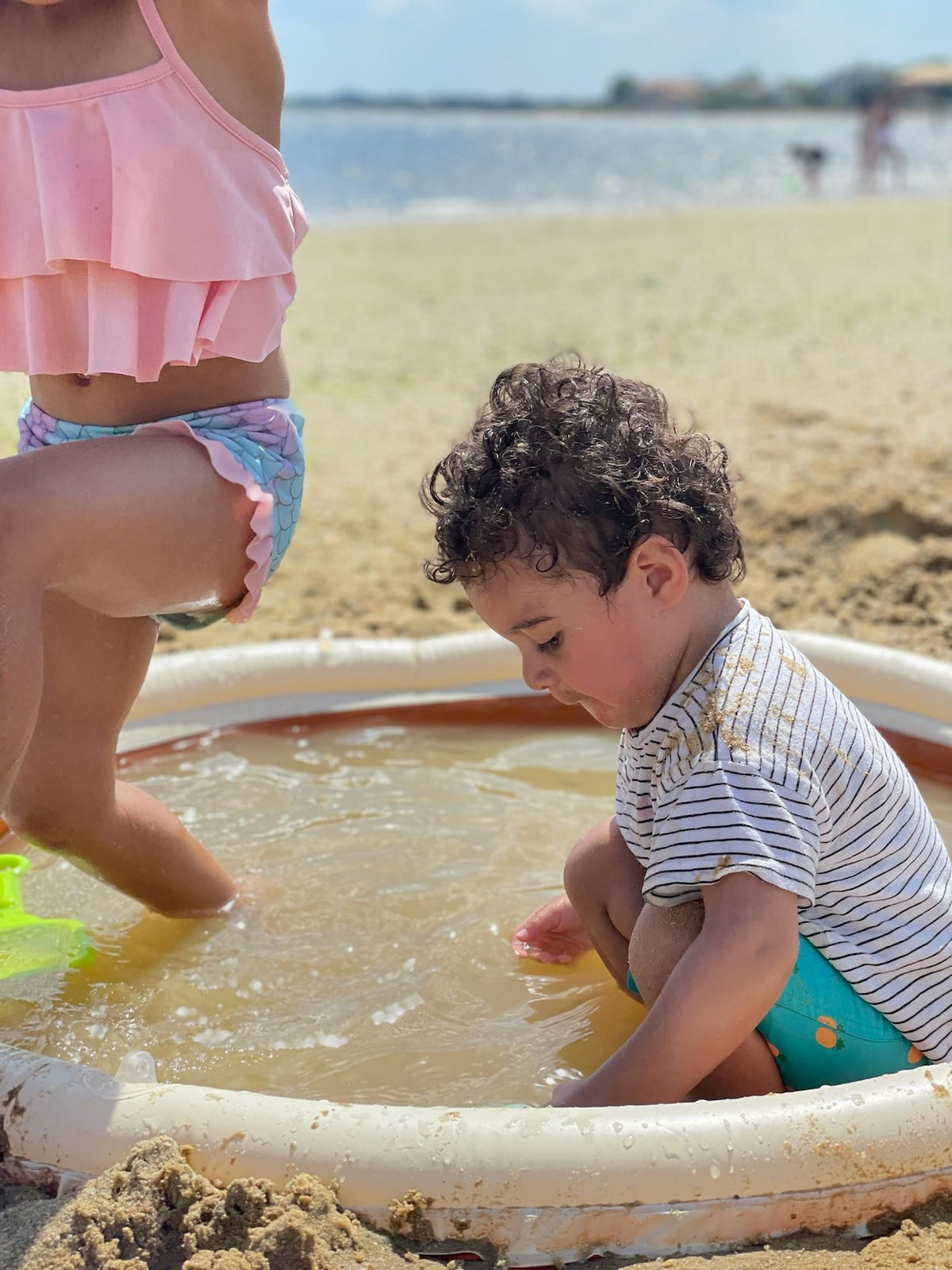 The Tiipikids Beach Pool in Stone, set up on a beach with two children filling it.